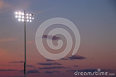 Stadium night lights over football field during sunset with cumulous clouds Stock Photo