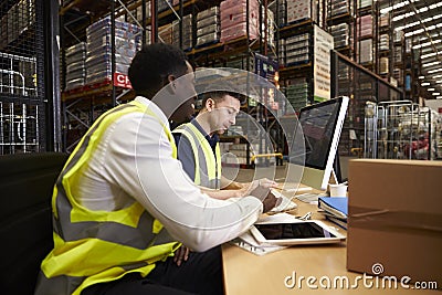 Staff managing warehouse logistics in an on-site office Stock Photo