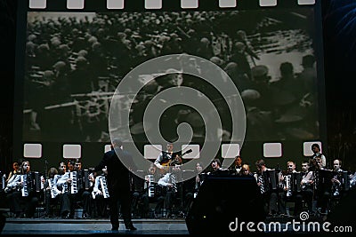 On stage, the musicians and soloists of Orchestra of accordionists (harmonic orchestra) under the baton of conductor. Editorial Stock Photo