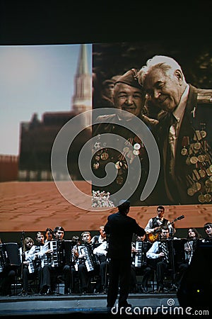 On stage, the musicians and soloists of Orchestra of accordionists (harmonic orchestra) under the baton of conductor. Editorial Stock Photo