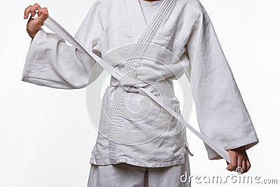 Stages of correct tying of the belt by a teenager on a sports kimono, step nine Stock Photo