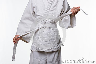 Stages of correct tying of the belt by a teenager on a sports kimono, step seven Stock Photo
