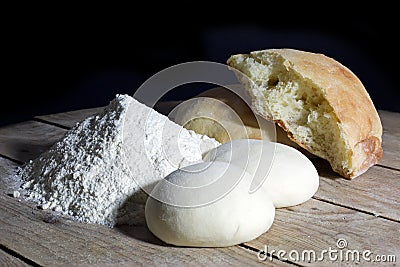 Stages of Making Bread-Flour, Dough and Loaf of Bread on Wooden Table Over Black Background Stock Photo