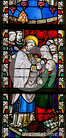 Stained Glass - Priest giving Holy Communion Editorial Stock Photo