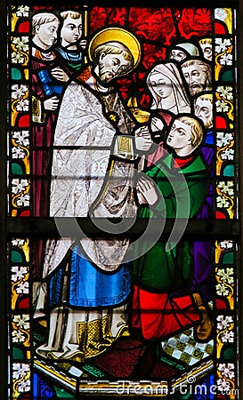 Stained Glass - Priest giving Holy Communion Editorial Stock Photo