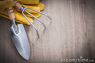Stainless hand trowel rake yellow leather safety gloves on wood Stock Photo
