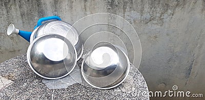 Stainless steel bowl putting and blue plastic watering can on stone table Stock Photo