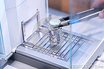 Stainless steel calibration weight to place on the analytical balance for calibration test Stock Photo