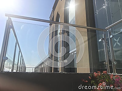 An Stainless steel glass transparent handrails with hairline finish fixed at lobby or entrance of multistory buildings and sky Stock Photo