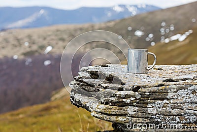 Stainless steel thermo mug on a flat stone within tne mountains Stock Photo