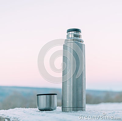 Stainless thermos and cup on snowy background. Stock Photo