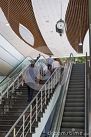 A staircase inside the railway station, visitors climb the stairs, a huge vintage clock is installed above the stairs. Editorial Stock Photo