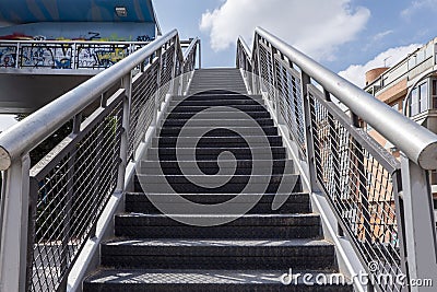 Stairs leading up to a metal walkway in an urban park next to a ring road Stock Photo
