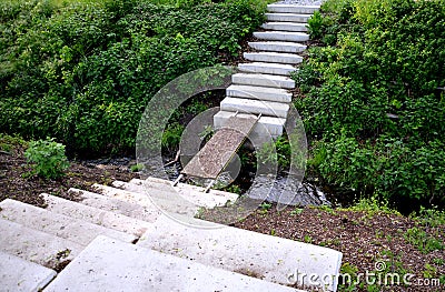Stairs to the deep riverbed on both sides formed by light concrete stairs, which are also seats. in between is an improvised footb Stock Photo