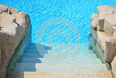 Stairs under clear water to step down into outdoor swimming pool. Stock Photo