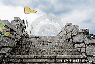 Stairway of stone wall with parapets and flags in cloudy afternoon Stock Photo