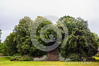 Stairway to heaven or nowhere - Old folly in England - mound covered with trees and stairs to top in beautiful green lawn Stock Photo