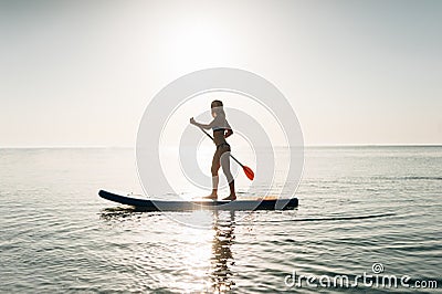 Stand up paddle board woman paddleboarding on Hawaii standing happy on paddleboard on blue water. Stock Photo