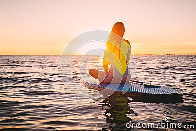 Stand up paddle boarding on a quiet sea with warm summer sunset colors. Relaxing on ocean Stock Photo