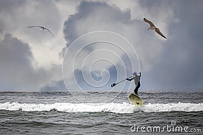 a stand up paddler surfing on an ocean wave Stock Photo