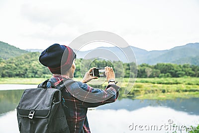 Standing back the Asian man using Camera smartphone Selfie taken of yourself connected to digital camera shooting photo Mountain Stock Photo