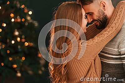 Standing and embracing. Lovely young couple are celebrating New Year at home Stock Photo