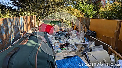 Standing inside a skip dumpster full of house clearance rubbish Stock Photo