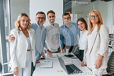 Standing together, looking into the camera and smiling. Group of professional business people is in the office Stock Photo