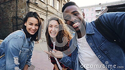 Standpunt van aantrekkelijke jonge mannen en vrouwenreizigers wordt geschoten die selfie in de straat stellende en lachende holdi stock footage Standpunt van aantrekkelijke jonge mannen en vrouwenreizigers wordt geschoten die selfie in de straat stellende en lachende holdi stock footage