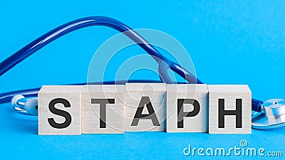 Staph word written on wooden blocks and stethoscope on light blue background Stock Photo