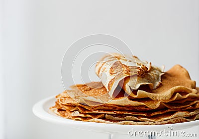 Staple of wheat golden yeast pancakes or crepes in a white plate closeup on a white background Stock Photo