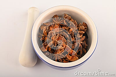 Star anise in a blue ceramic spice mortar with a pestle on a white background. Close up Stock Photo