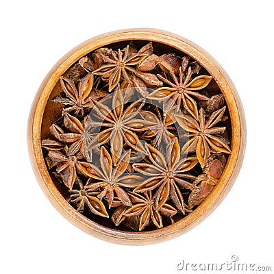 Star anise fruits and seeds, pericarps of Illicium verum, in wooden bowl Stock Photo