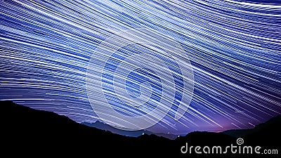 Star trail effect over mountain night sky. Stock Photo