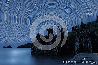 Star Trails Against rugged rocks silhouette Stock Photo