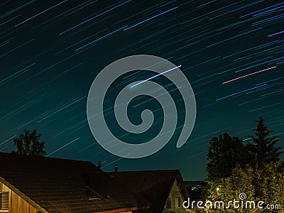 Star trails on the roofs of a Swiss village in Summer Stock Photo