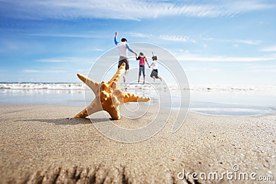 Starfish In Foreground As Father Plays With Children In Sea Stock Photo