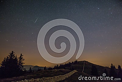 Starry Night Sky and Shooting Stars over Mountains Stock Photo