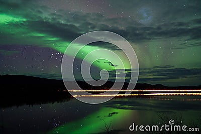 Stars and Northern Lights over dark Road at Lake Stock Photo