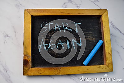 Start Again write on a chalkboard isolated on wooden table Stock Photo