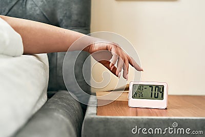Start of the day. Close up of hand of woman reaching snooze button on digital alarm clock in early morning Stock Photo