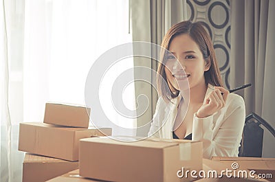 Start up business woman sitting in a desk full of delivery boxes Stock Photo