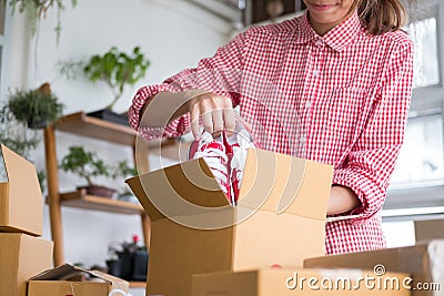 start up small business owner packing shoes in the box at workplace. freelance woman entrepreneur SME seller prepare product for Stock Photo