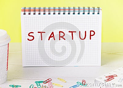 Startup - word concept on a checkered notebook on a yellow background Stock Photo