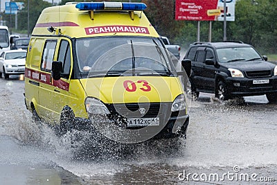 State Emergency Ambulance Reanimation Medical vehicle driving to help patient on city street road over deep muddy puddle, splashin Editorial Stock Photo