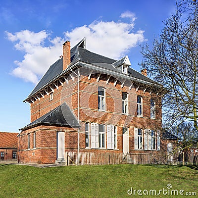 Stately parsonage againts a blue sky with dramatic clouds, Ravels, Belgium Stock Photo