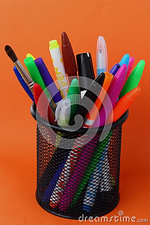 Stationery glass with felt-tip pens on an orange background Stock Photo