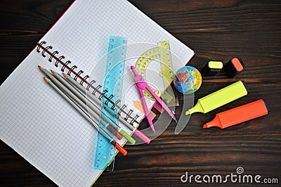 Stationery scattered on a notebook lying on a dark wooden table, Stock Photo