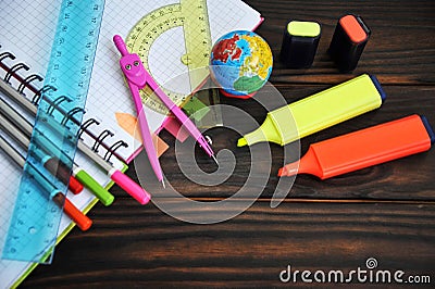 Stationery scattered on a notebook lying on a wooden table Stock Photo