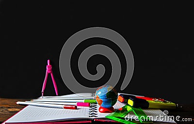 Stationery scattered on a notebook lying on a wooden table on the background of a board Stock Photo